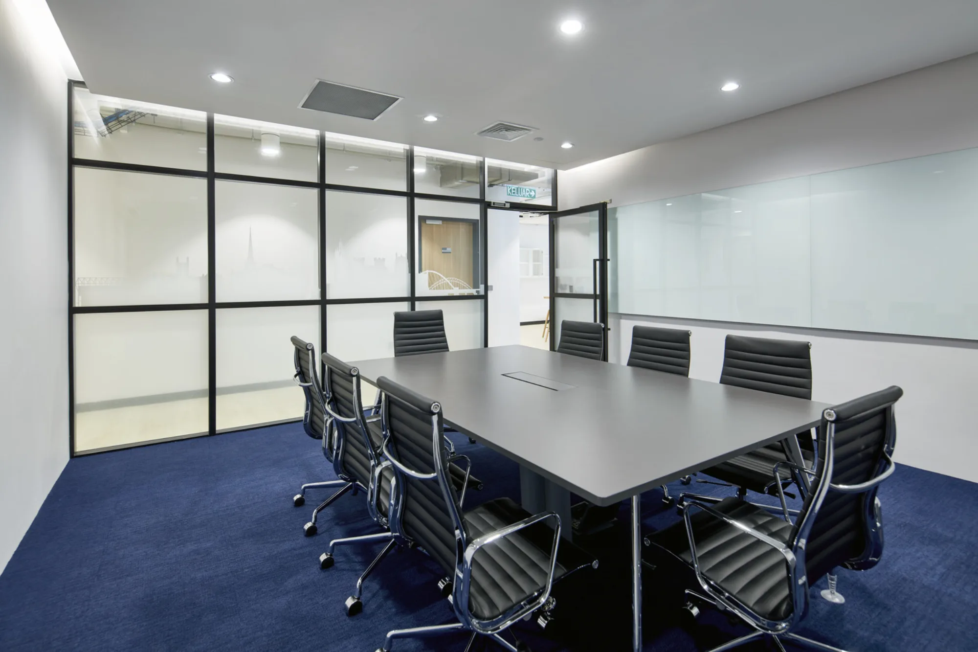 Carpeted meeting room with rectangular table, office chairs, and long whiteboard
