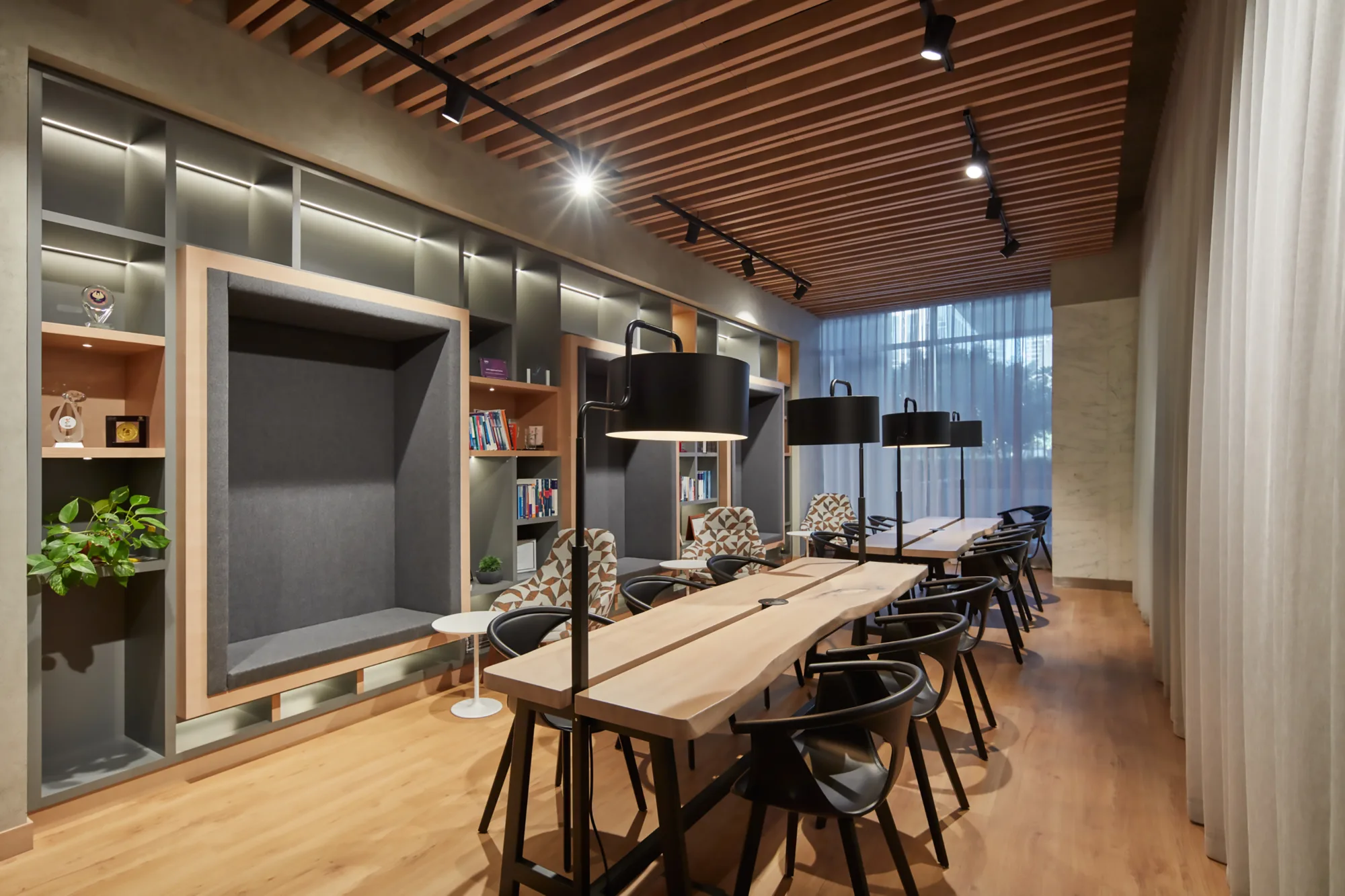 PWC Middle East reading area with chairs and a long table. Books and award plaques are also present in the shelves.