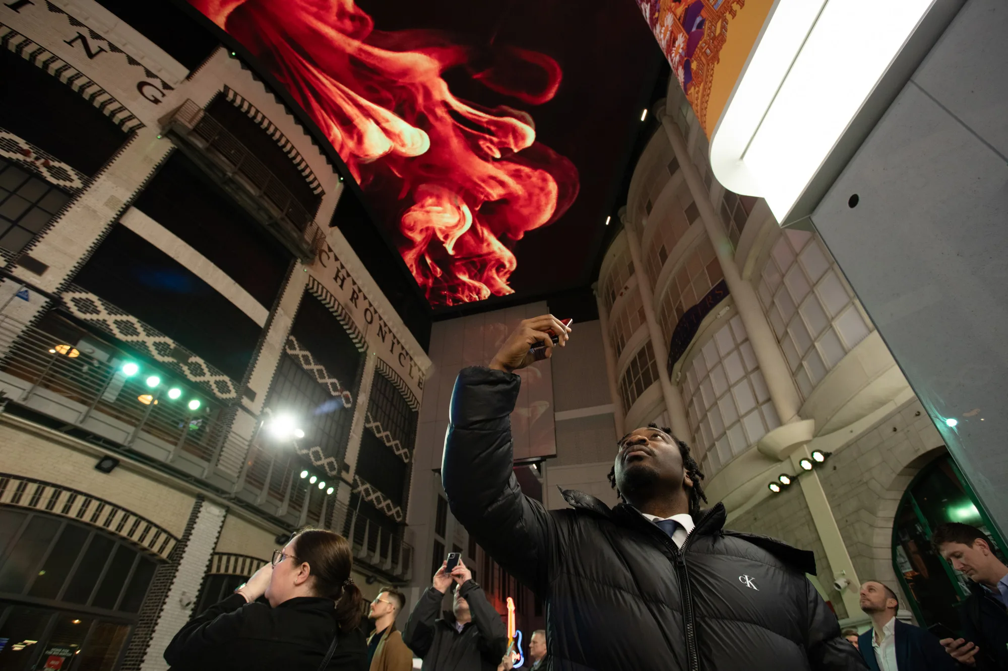 People looking up and photographing the illuminated ceiling