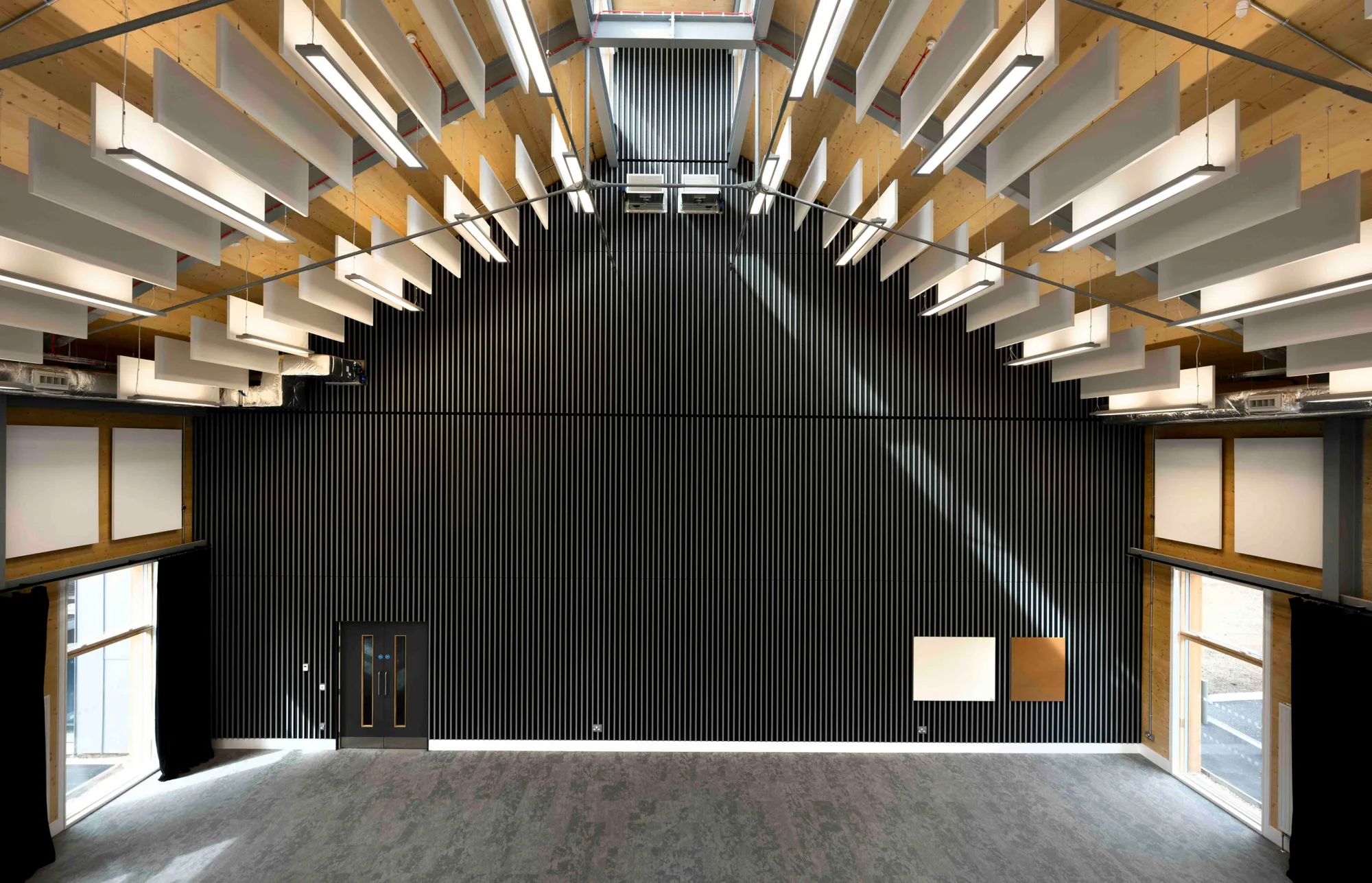 Interior view of the Royal Military Academy Sandhurst Music Facility featuring a modern design with high ceilings, wooden beams and acoustic panels