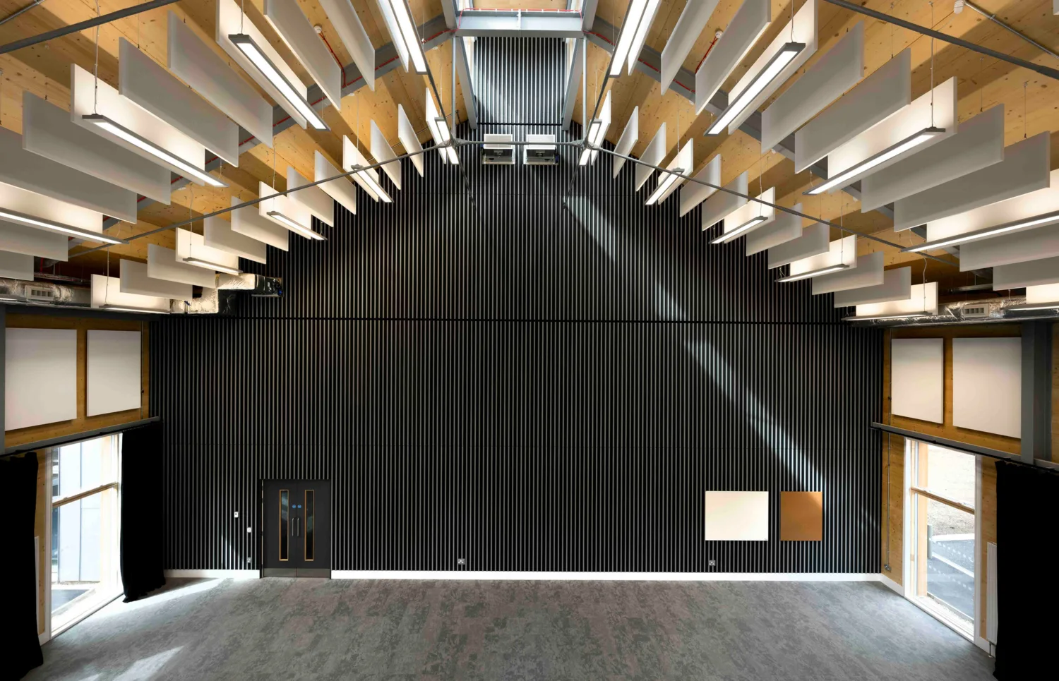 Interior view of the Royal Military Academy Sandhurst Music Facility featuring a modern design with high ceilings, wooden beams and acoustic panels