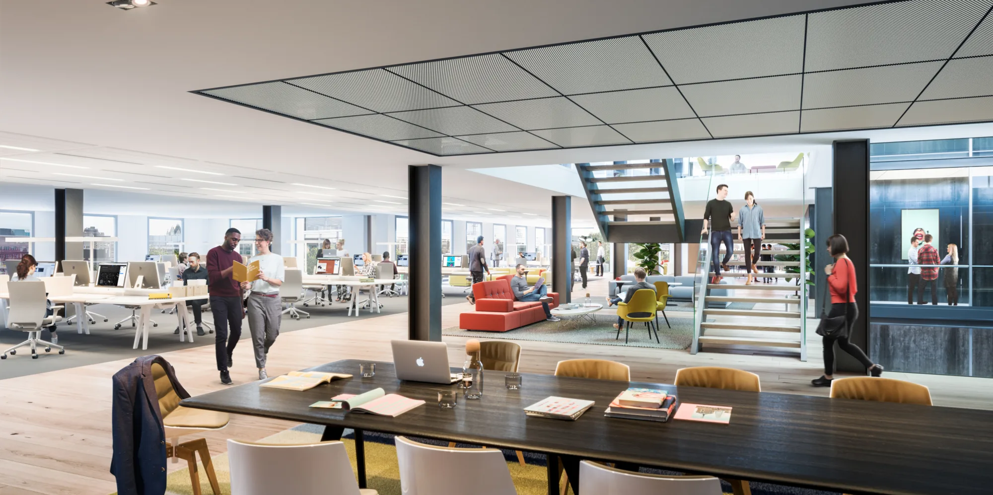 An open-plan office, showing banks of desks to the right and a large table with chairs on the left. Staircase leading to the upper floor with light coming down