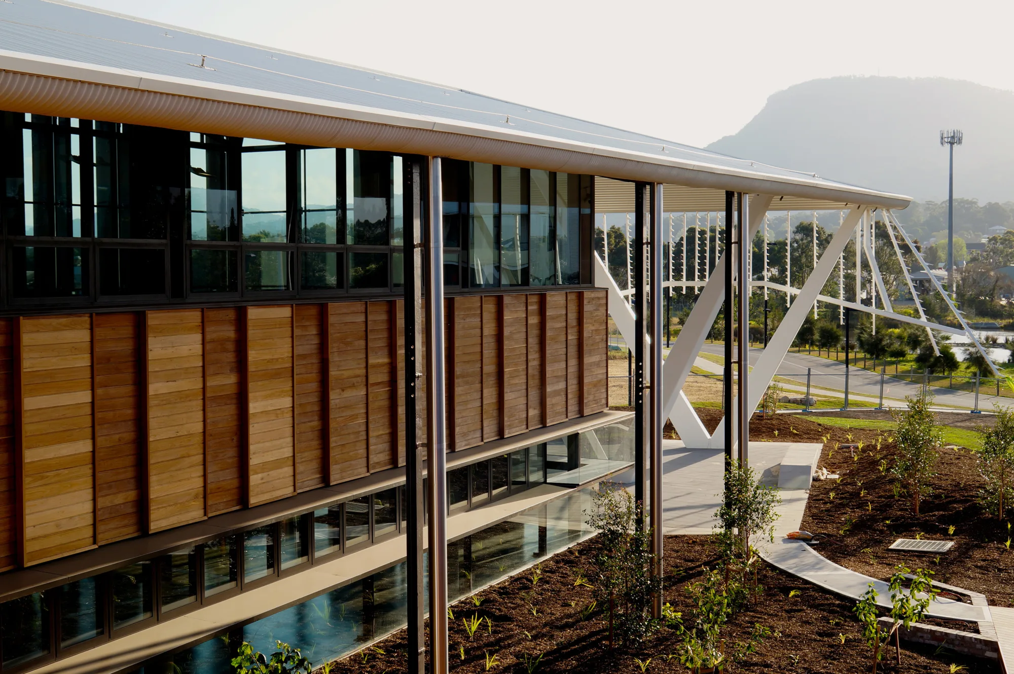 View of building's exterior wooden cladding and metal annex in freshly landscaped garden.