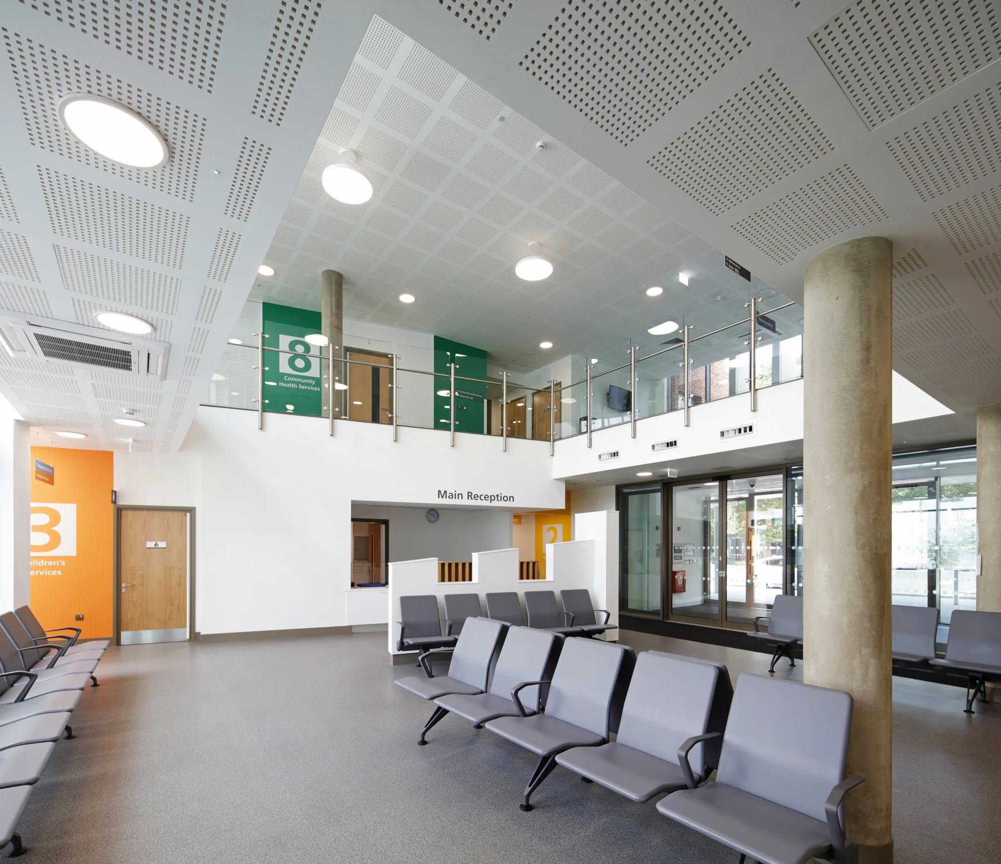 Main reception desk with rows of grey chairs in the waiting room in the foreground