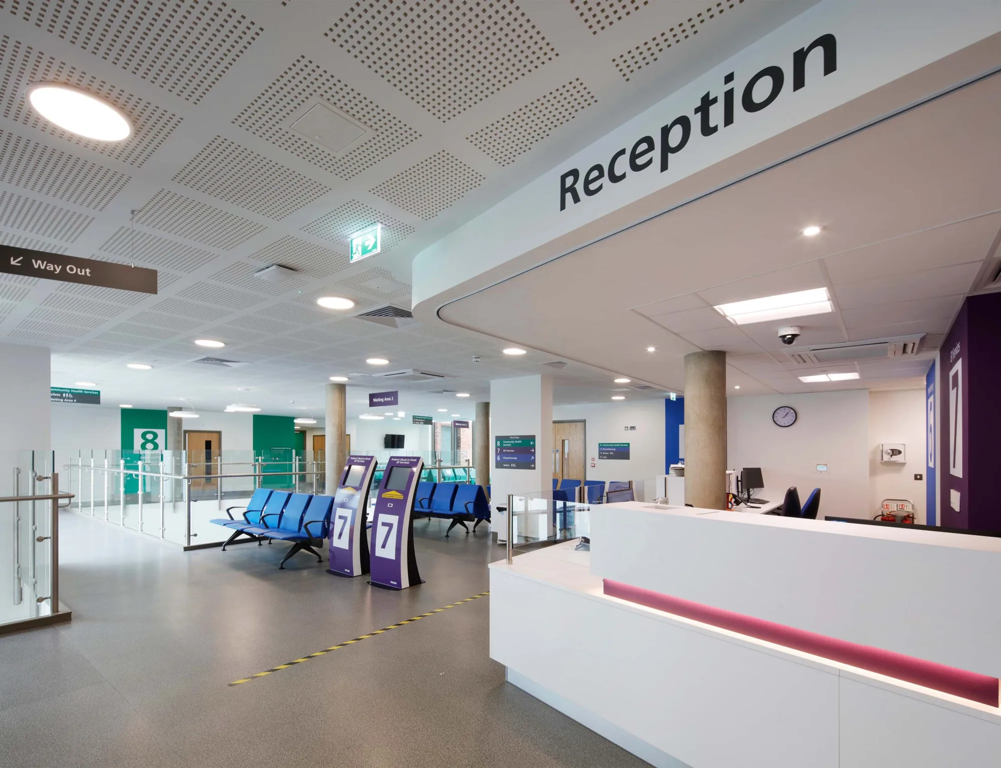 Reception desk with signage above and blue chairs in rows in the waiting room