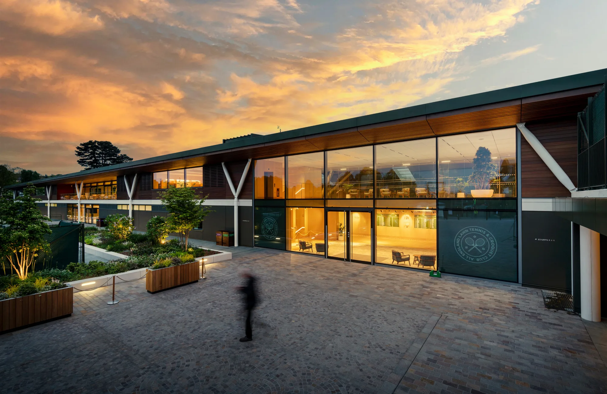 Exterior view of the Tennis Centre at dusk with warm orange lighting