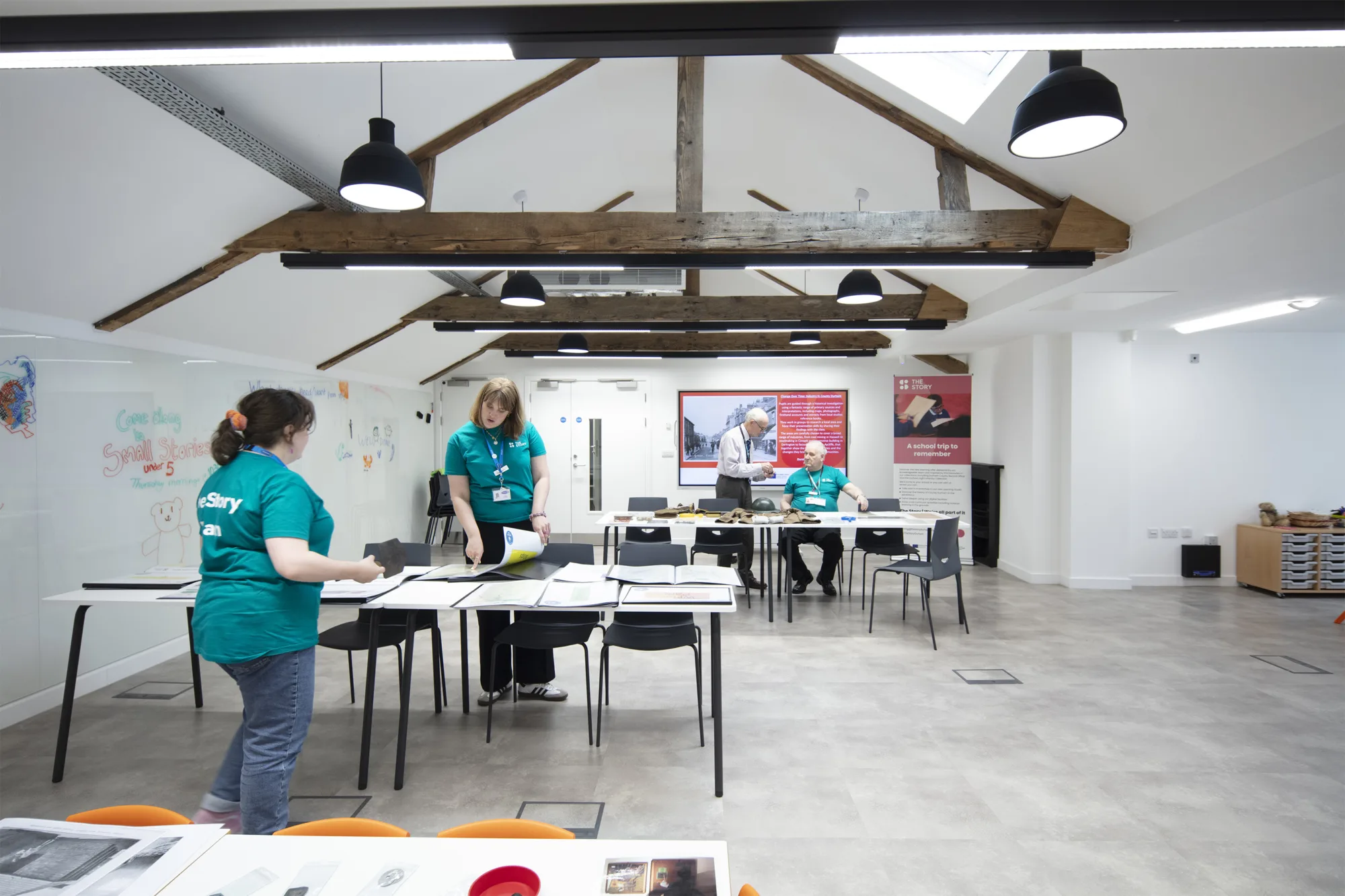 Two men and two women collaborate at a tables inside The Story, a bright, modern workspace.