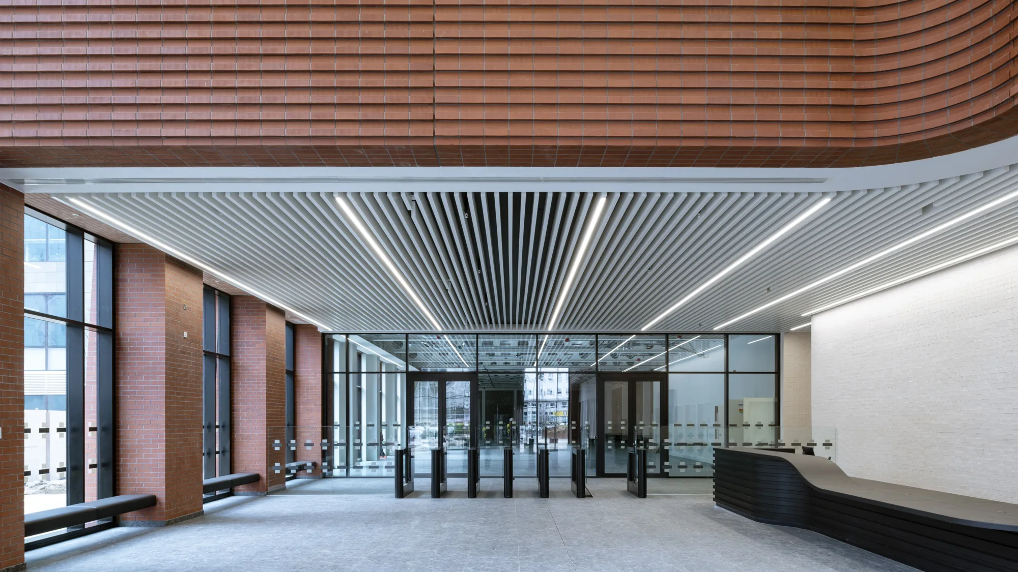 Internal lobby with red bricked walls and a glass doored lobby and grey carpet