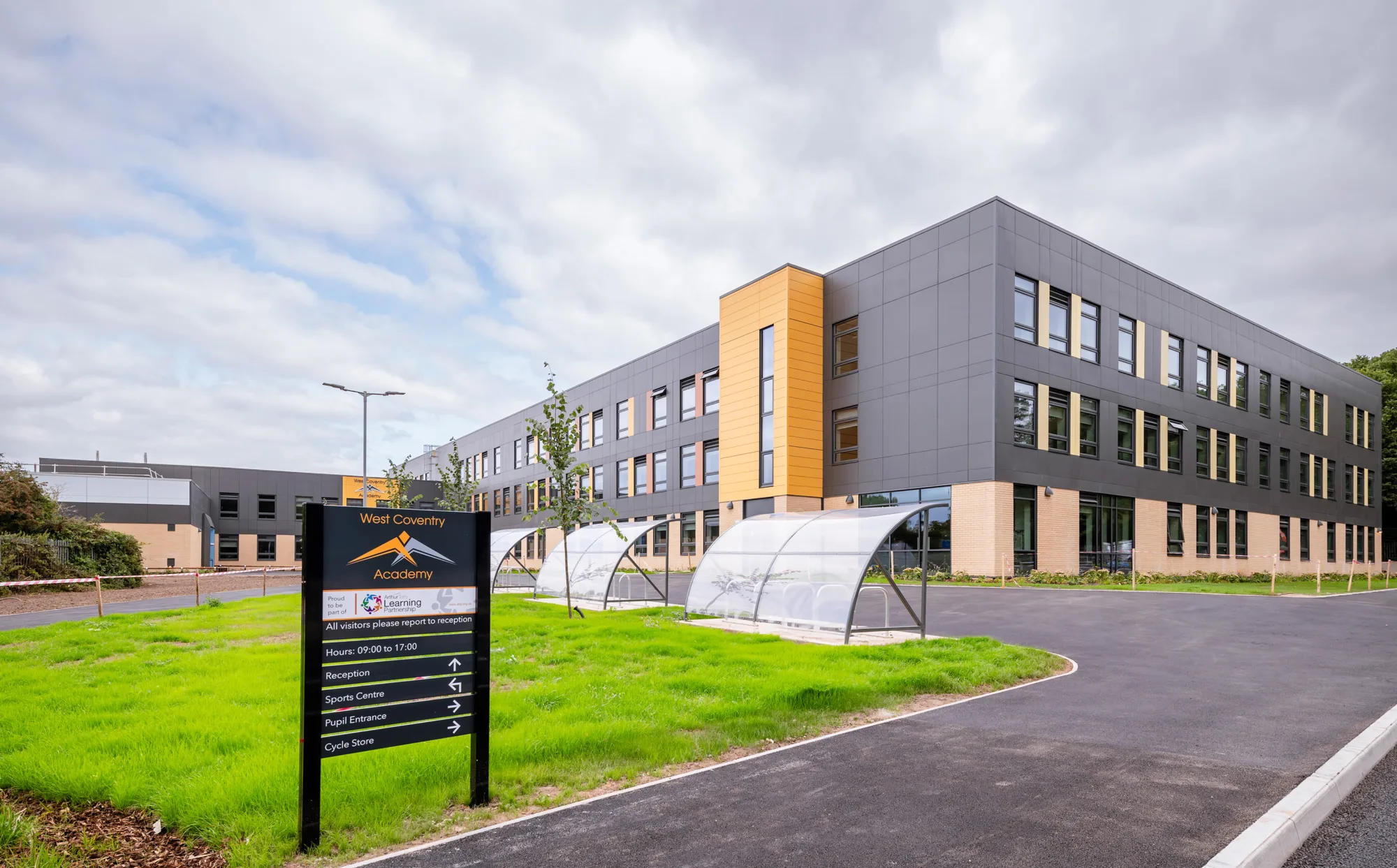 Exterior of the building with bike racks, a green and wayfinding signage