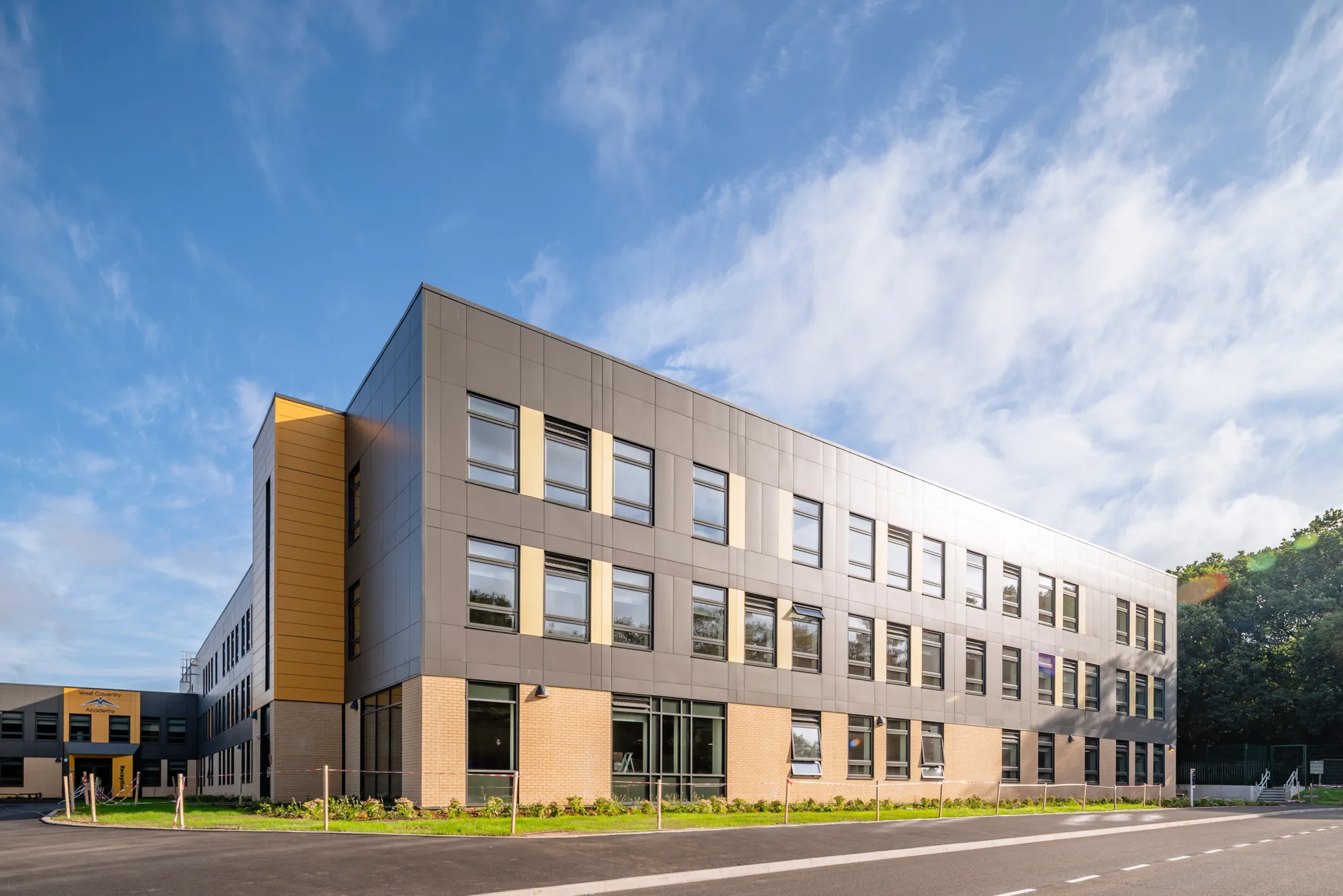Exterior of the building with a grass area, pavement and road in the foreground