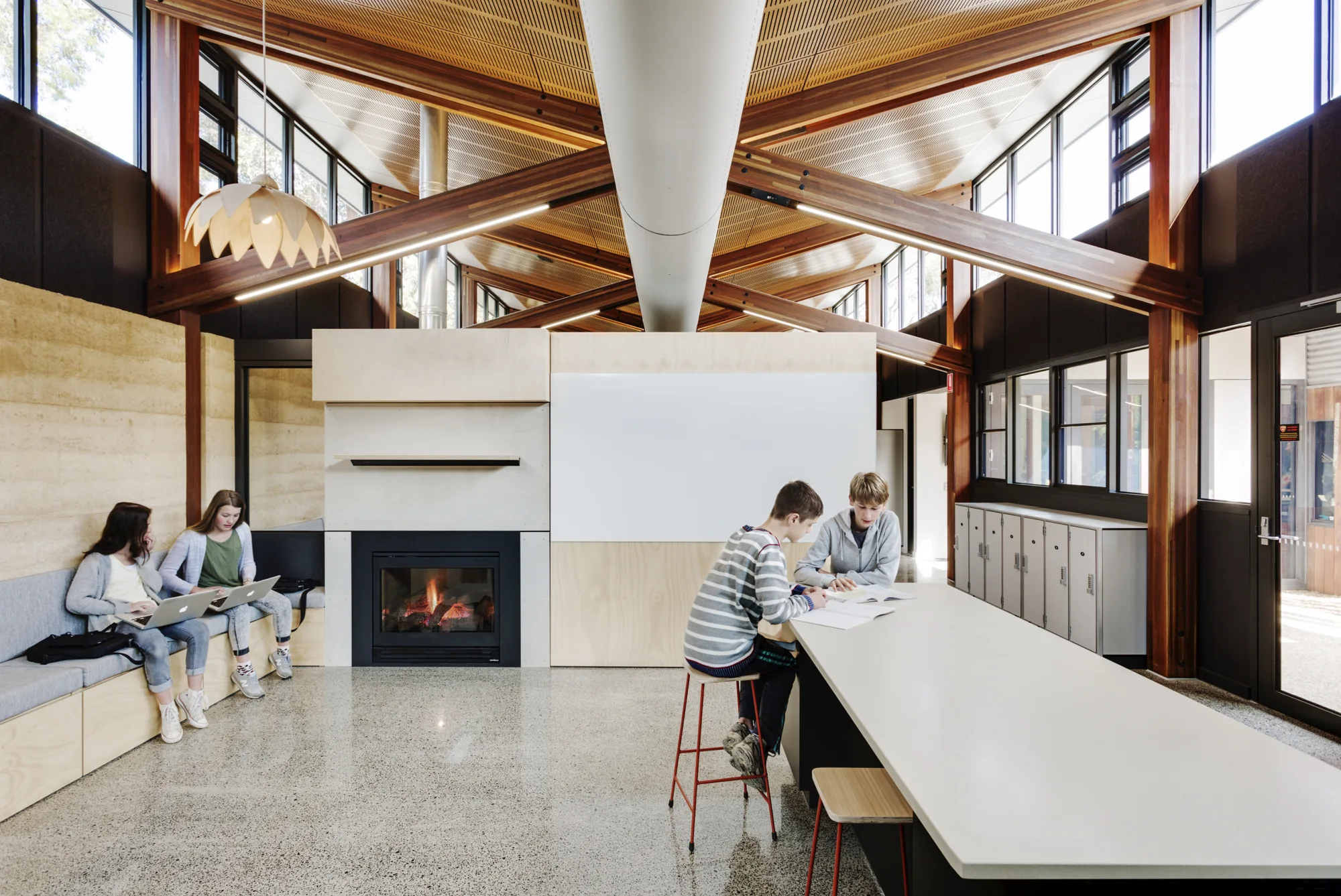 Interior of a homestead at Woodleigh school showing pupils using the area for study next to a fire