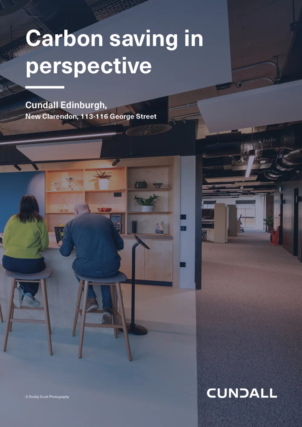 Office setting with two people seated on stools at a high table using laptops; background includes shelves with plants and books. Text reads: “Carbon saving in perspective. Cundall Edinburgh, New Clarendon, 113–116 George Street.” CUNDALL logo in bottom right.