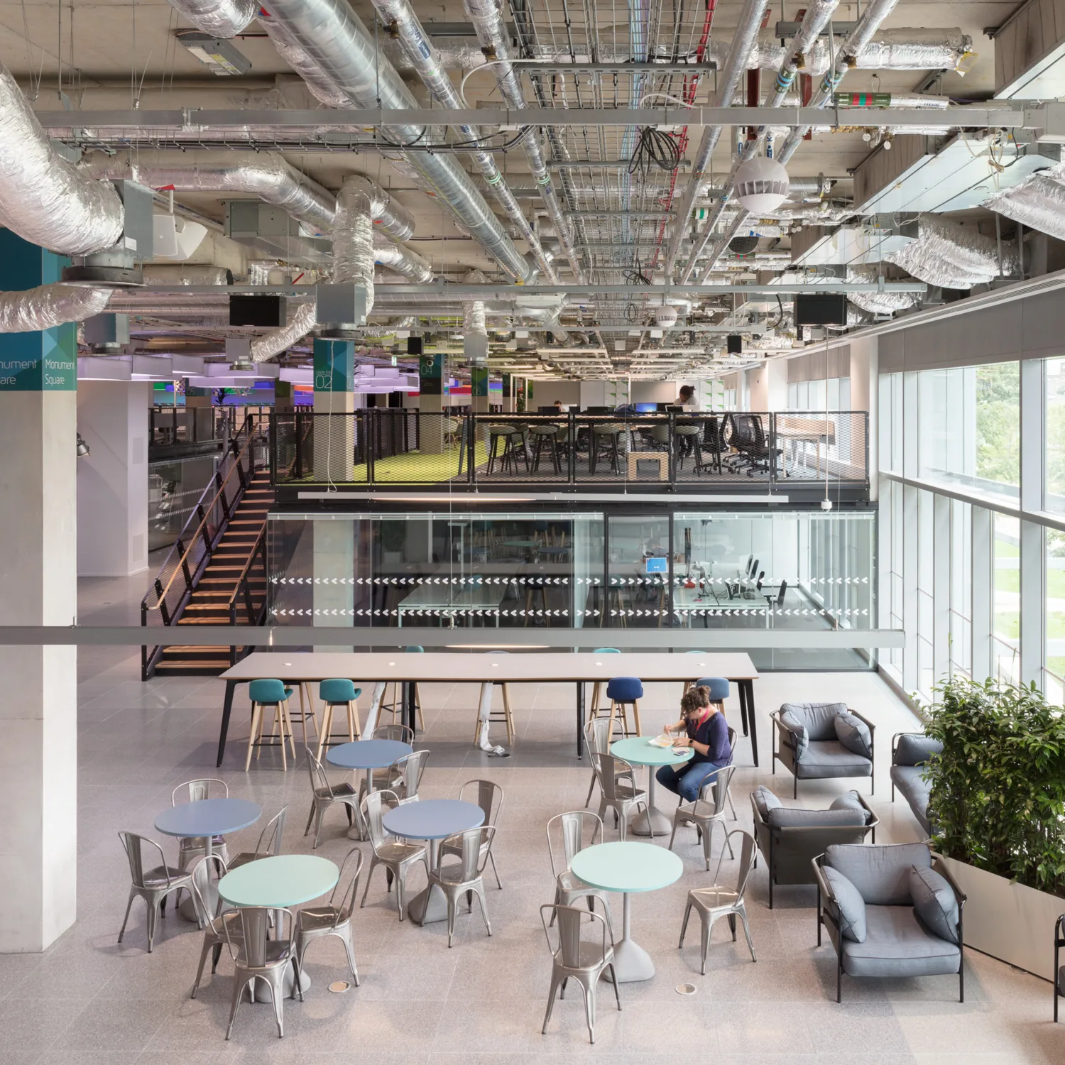 Plexal office interior with desks, exposed ceiling beams and glass façade
