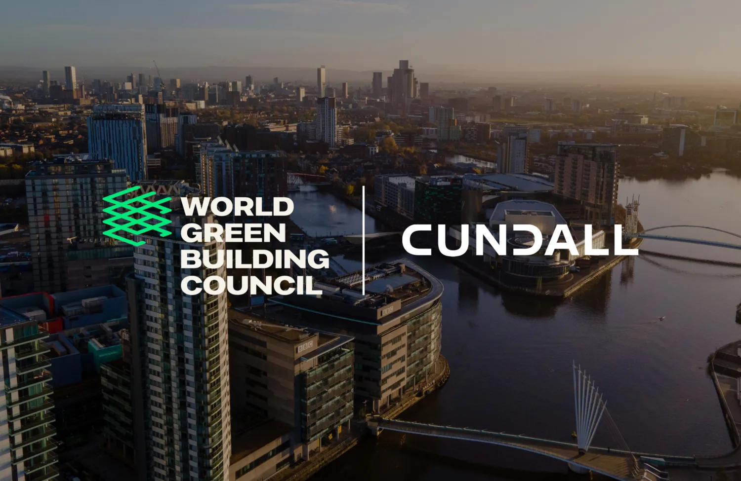 Aerial view of a modern cityscape with high-rise buildings along a river, bridges crossing the water, and urban streets. The image includes two logos: “World Green Building Council” in white and green on the left and “Cundall” in white on the right, positioned over the city background.