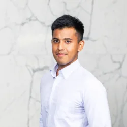 head and shoulders image of Gerald wearing a white shirt in front of a marble wall