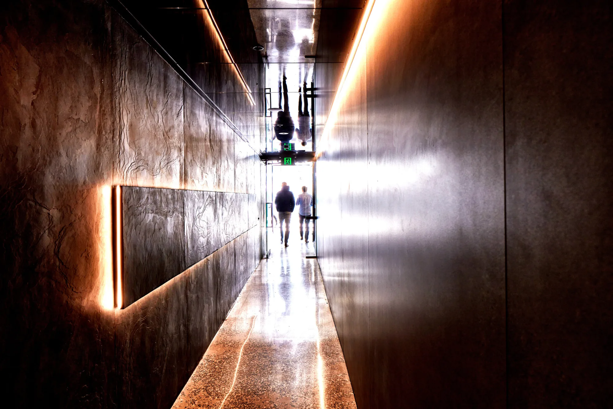 Dark shiny corridor lit with warm, bold lighting